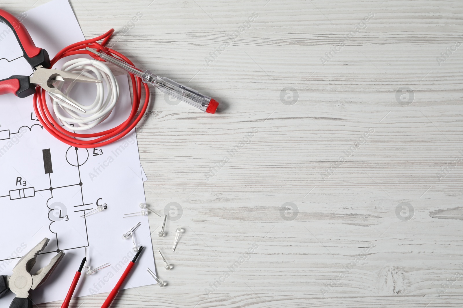 Photo of Different electrical tools and circuit diagrams on light wooden table, flat lay. Space for text