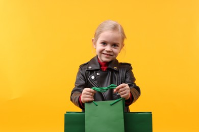 Photo of Little girl with shopping bags on orange background