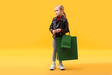 Photo of Little girl with shopping bags on orange background