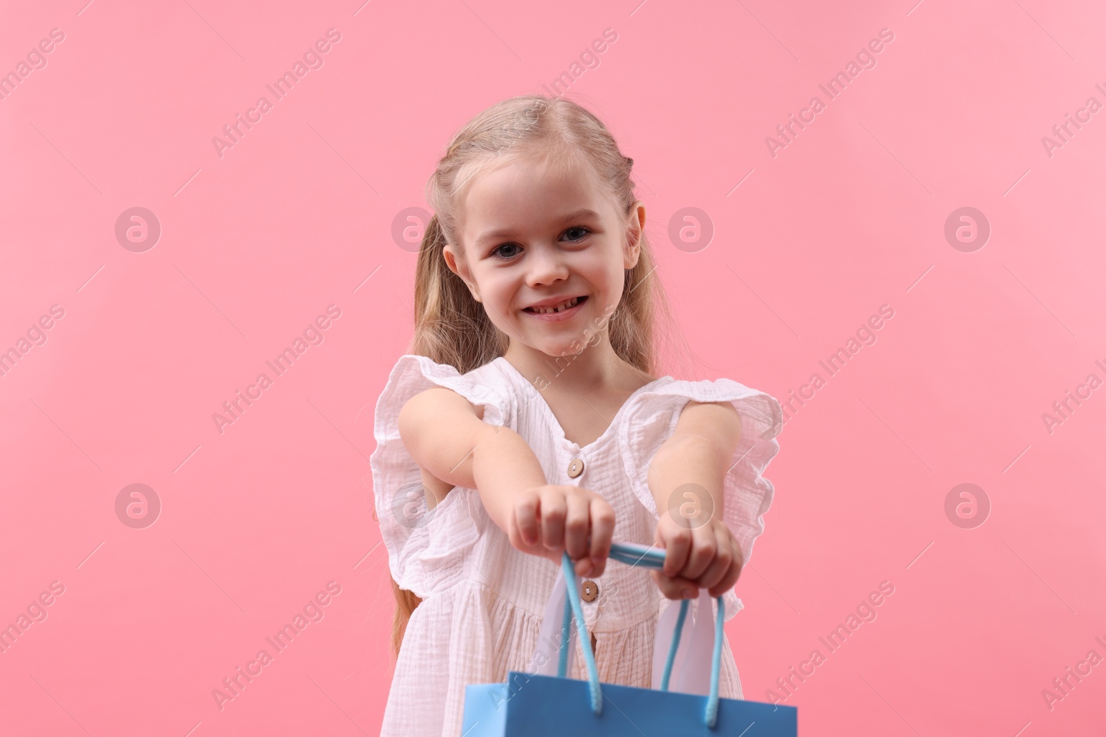 Photo of Little girl with shopping bag on pink background