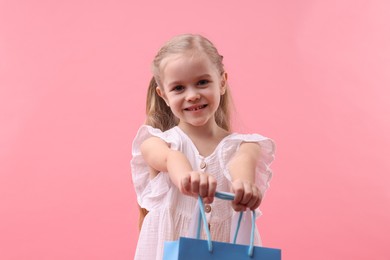 Little girl with shopping bag on pink background