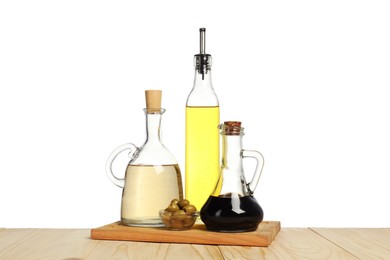 Photo of Salad dressings and olives on wooden table against white background