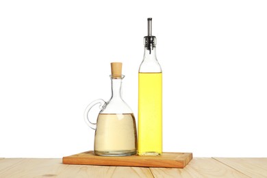 Photo of Oil and vinegar in bottles on wooden table against white background