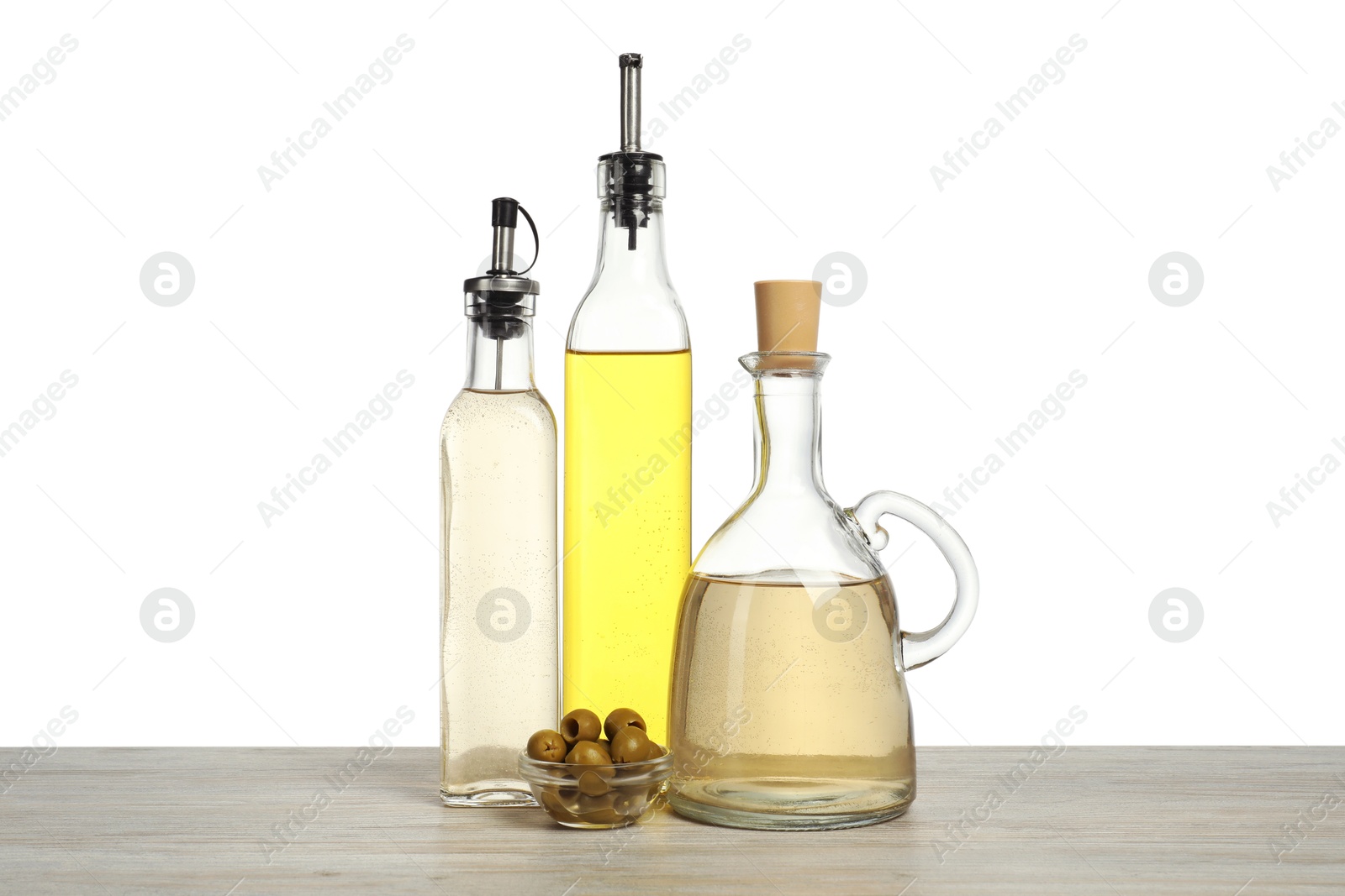 Photo of Salad dressings and olives on wooden table against white background