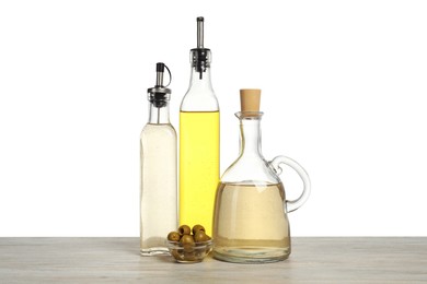 Photo of Salad dressings and olives on wooden table against white background