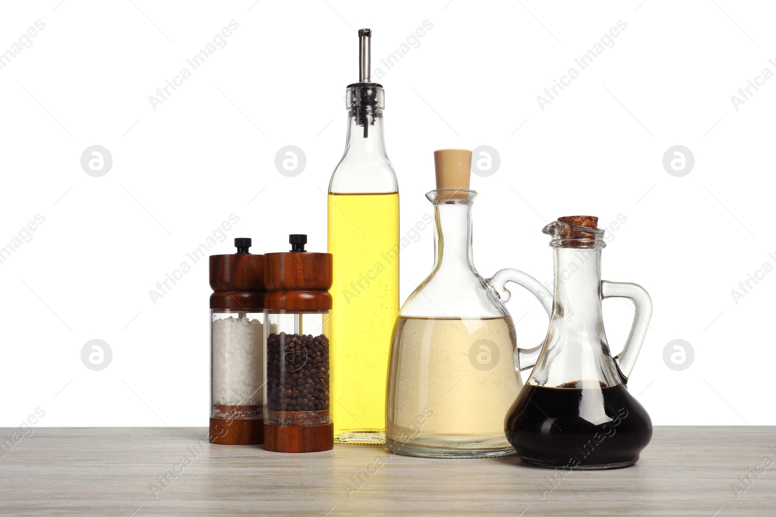 Photo of Salad dressings and spices on wooden table against white background