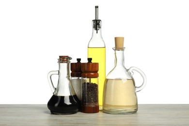 Photo of Salad dressings and spices on wooden table against white background