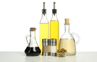 Photo of Salad dressings, spices and olives on table against white background