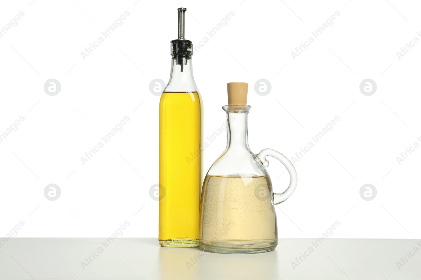 Photo of Oil and vinegar in bottles on table against white background