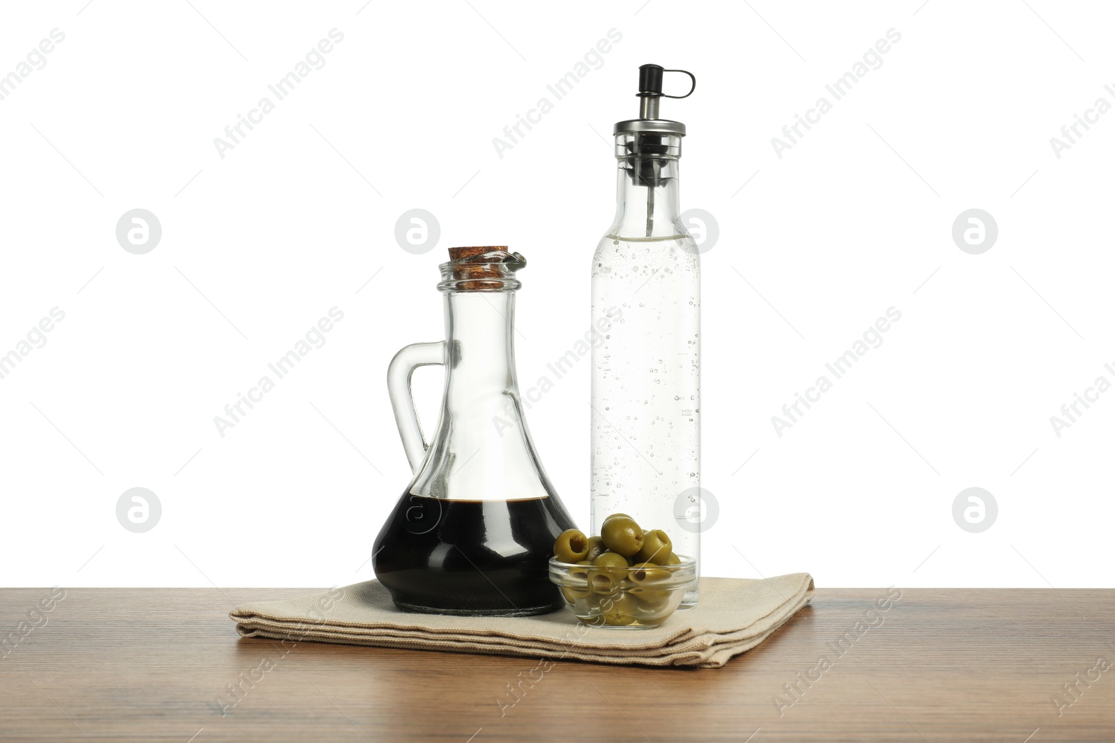 Photo of Salad dressings and olives on wooden table against white background