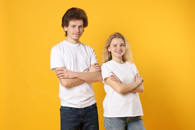 Photo of Young woman and man wearing blank white t-shirts on orange background. Mockup for design