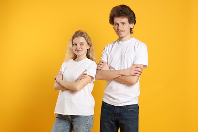 Photo of Young woman and man wearing blank white t-shirts on orange background. Mockup for design