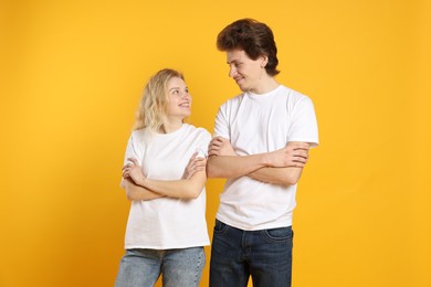 Photo of Young woman and man wearing blank white t-shirts on orange background. Mockup for design