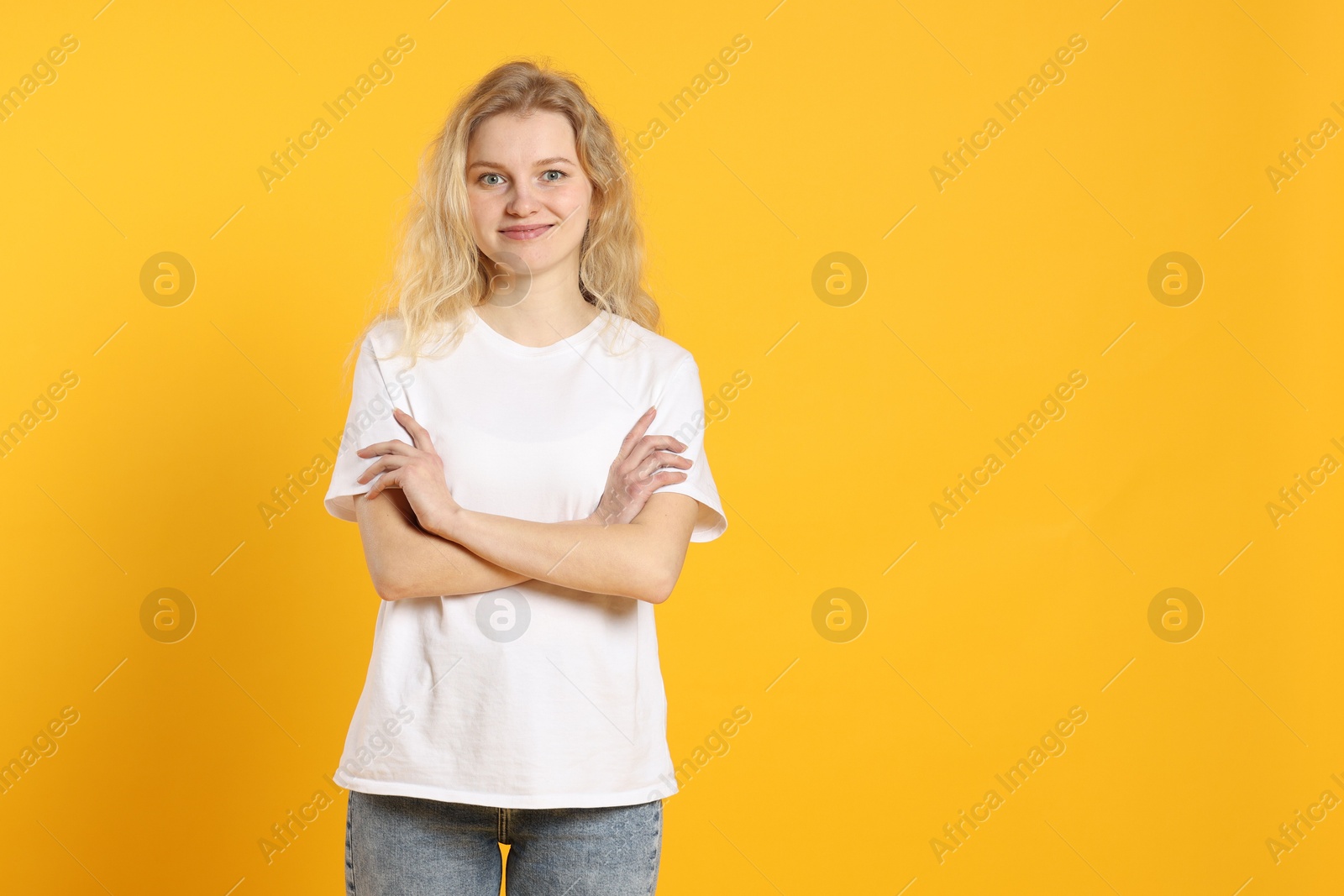 Photo of Young woman wearing blank white t-shirt on orange background. Mockup for design