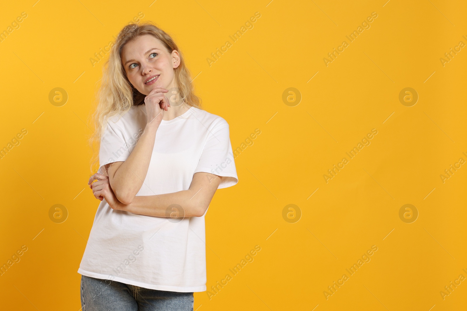 Photo of Young woman wearing blank white t-shirt on orange background. Mockup for design