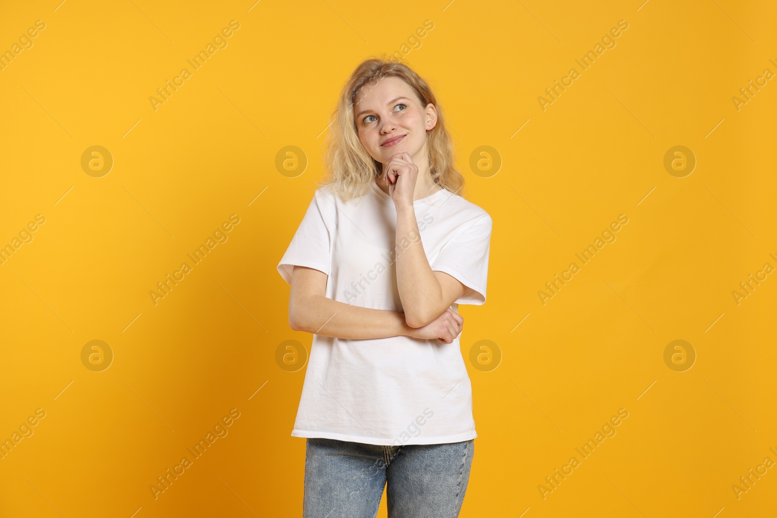 Photo of Young woman wearing blank white t-shirt on orange background. Mockup for design