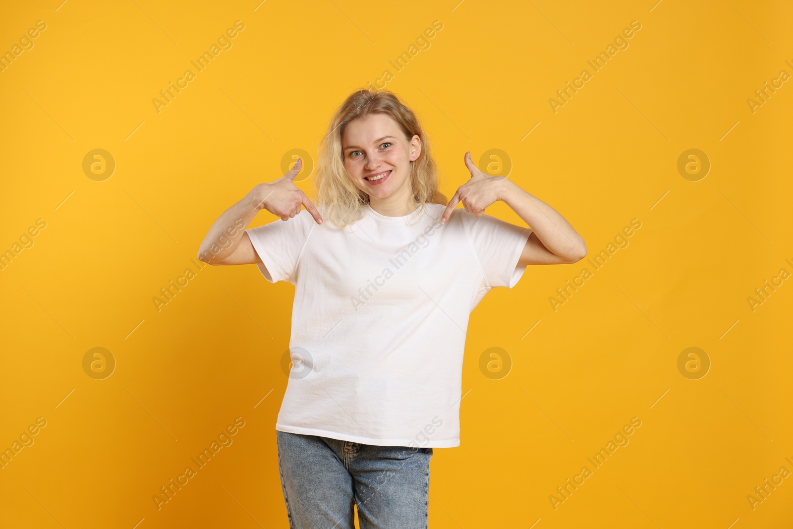 Photo of Young woman wearing blank white t-shirt on orange background. Mockup for design