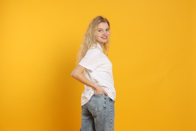 Photo of Young woman wearing blank white t-shirt on orange background. Mockup for design