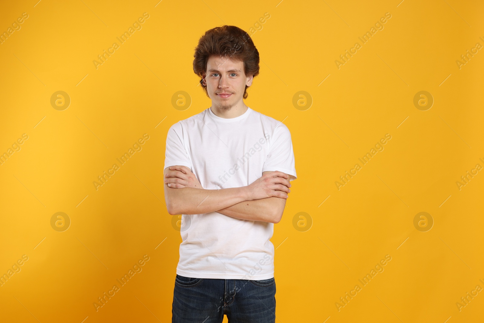 Photo of Young man wearing blank white t-shirt on orange background. Mockup for design