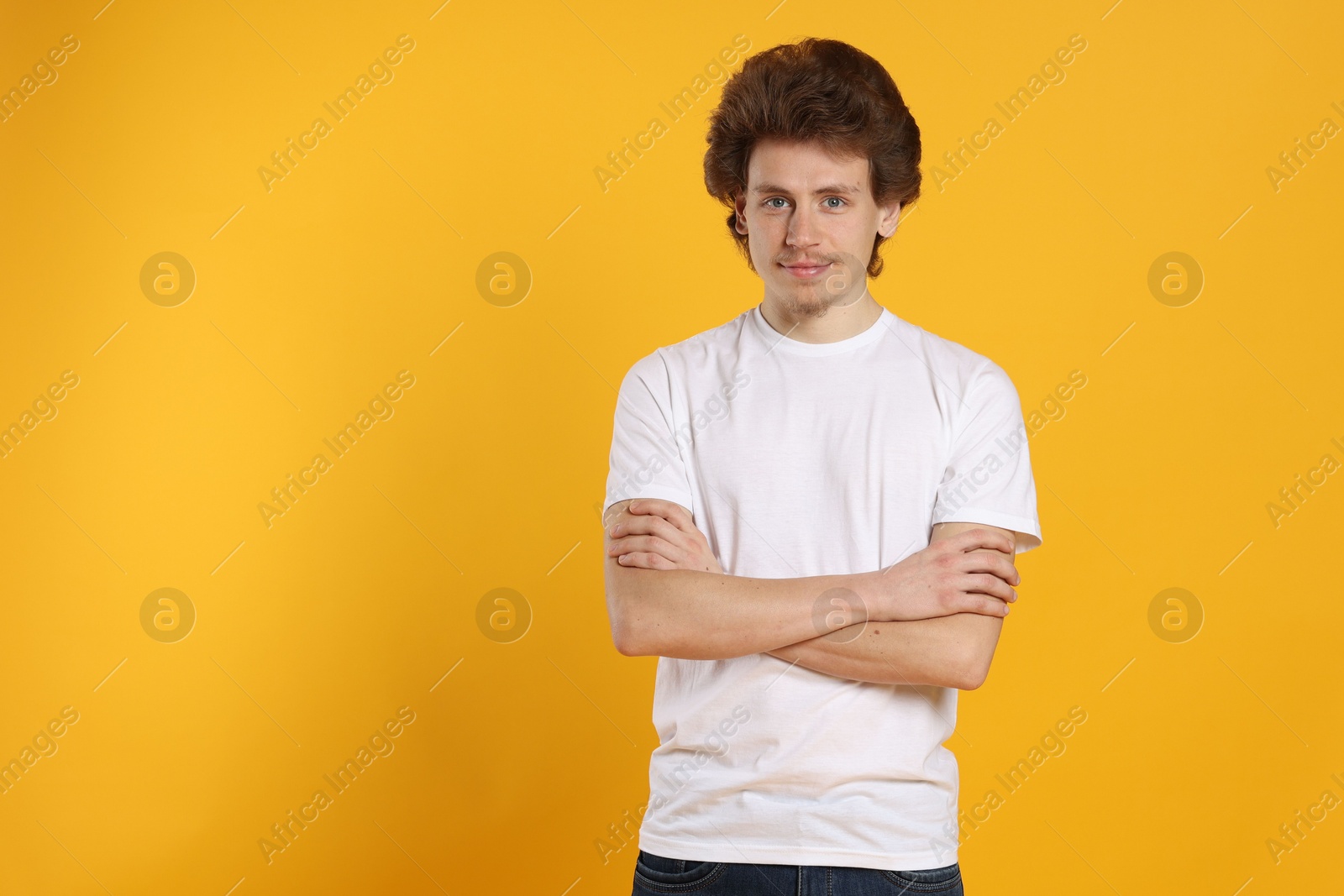 Photo of Young man wearing blank white t-shirt on orange background. Mockup for design