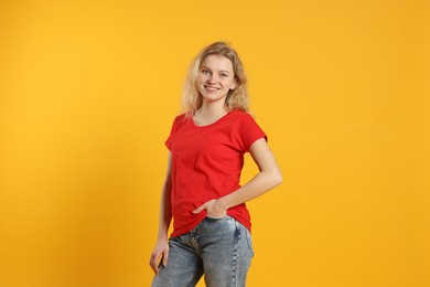 Photo of Young woman wearing blank red t-shirt on orange background. Mockup for design