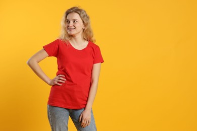 Photo of Young woman wearing blank red t-shirt on orange background. Mockup for design