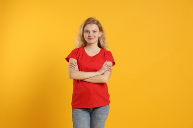 Photo of Young woman wearing blank red t-shirt on orange background. Mockup for design