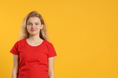 Photo of Young woman wearing blank red t-shirt on orange background. Mockup for design