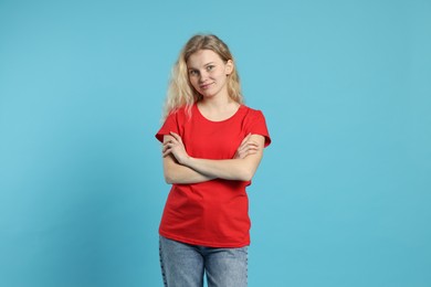 Photo of Young woman wearing blank red t-shirt on light blue background. Mockup for design