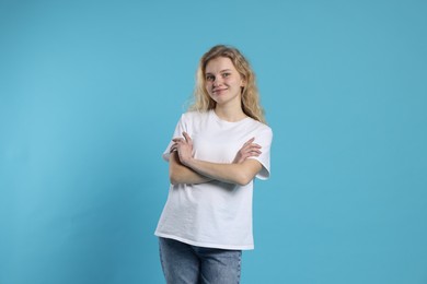 Photo of Young woman wearing blank white t-shirt on light blue background. Mockup for design