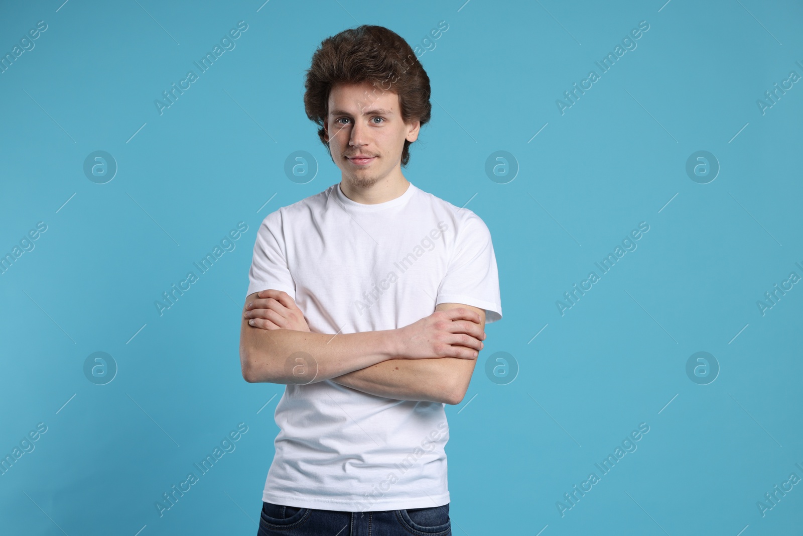 Photo of Young man wearing blank white t-shirt on light blue background. Mockup for design