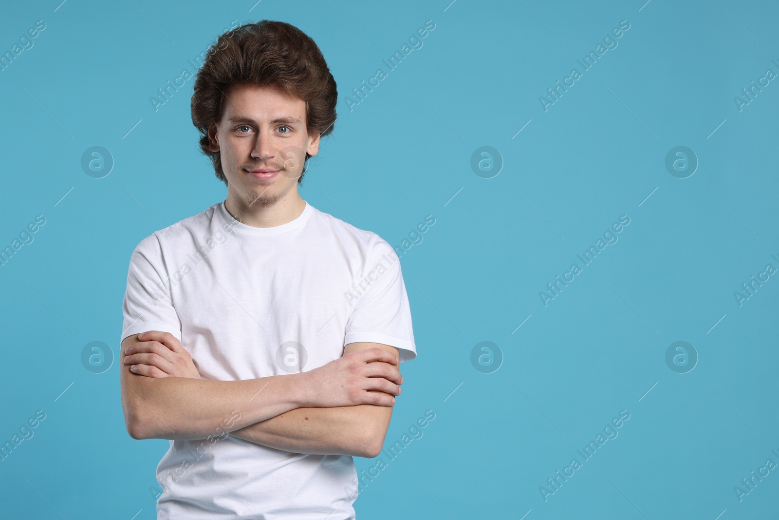 Photo of Young man wearing blank white t-shirt on light blue background. Mockup for design