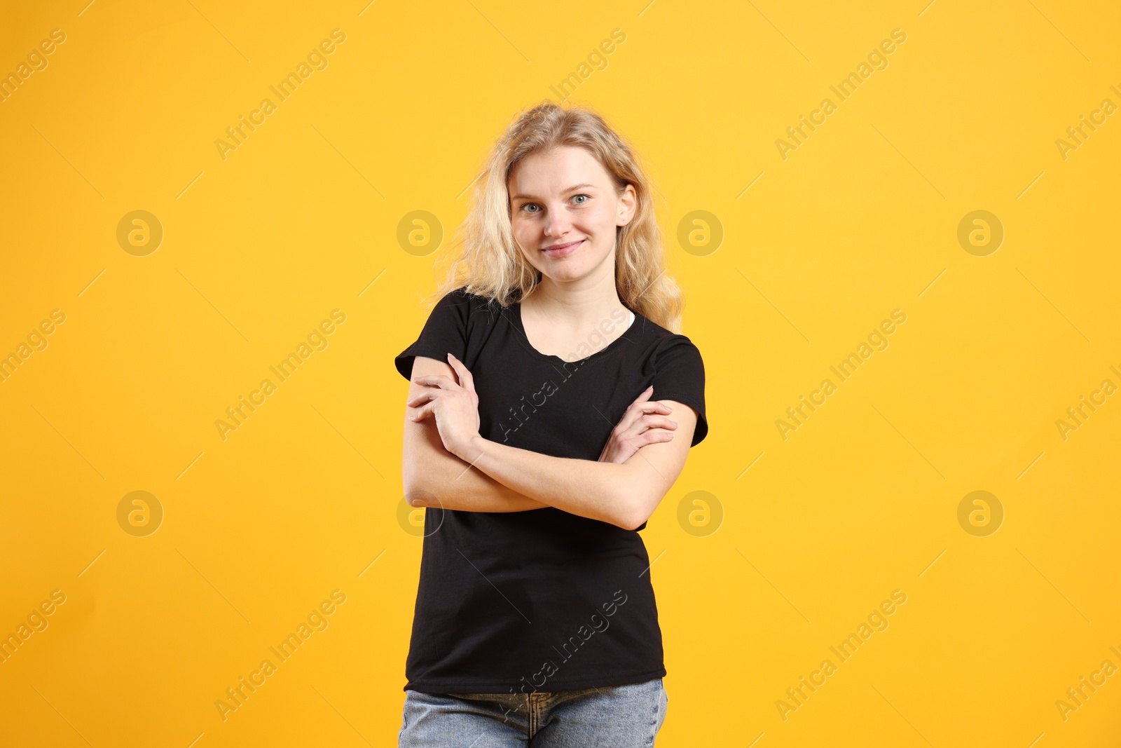 Photo of Young woman wearing blank black t-shirt on orange background. Mockup for design