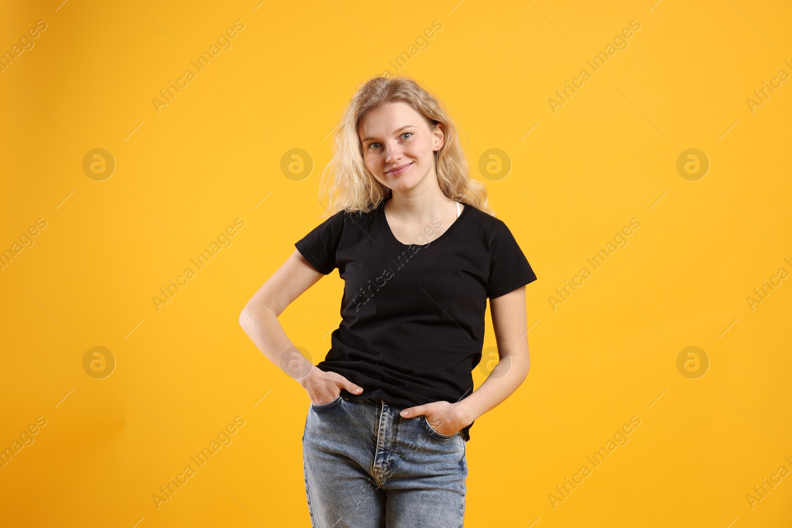 Photo of Young woman wearing blank black t-shirt on orange background. Mockup for design