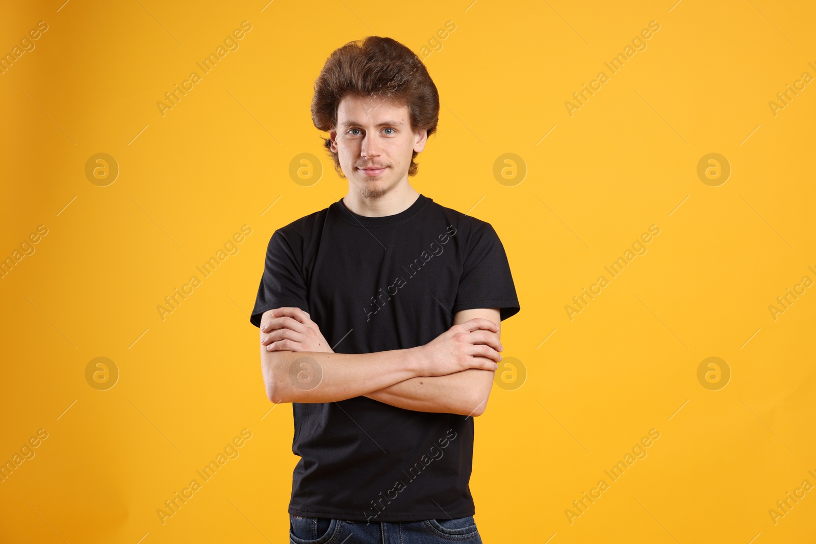 Photo of Young man wearing blank black t-shirt on orange background. Mockup for design