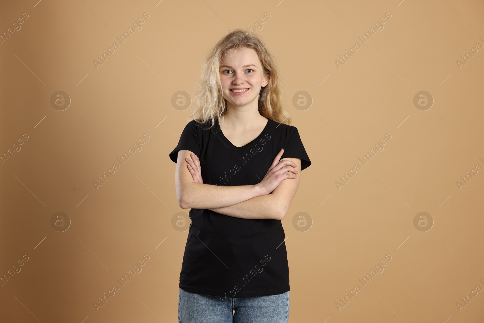 Photo of Young woman wearing blank black t-shirt on light brown background. Mockup for design