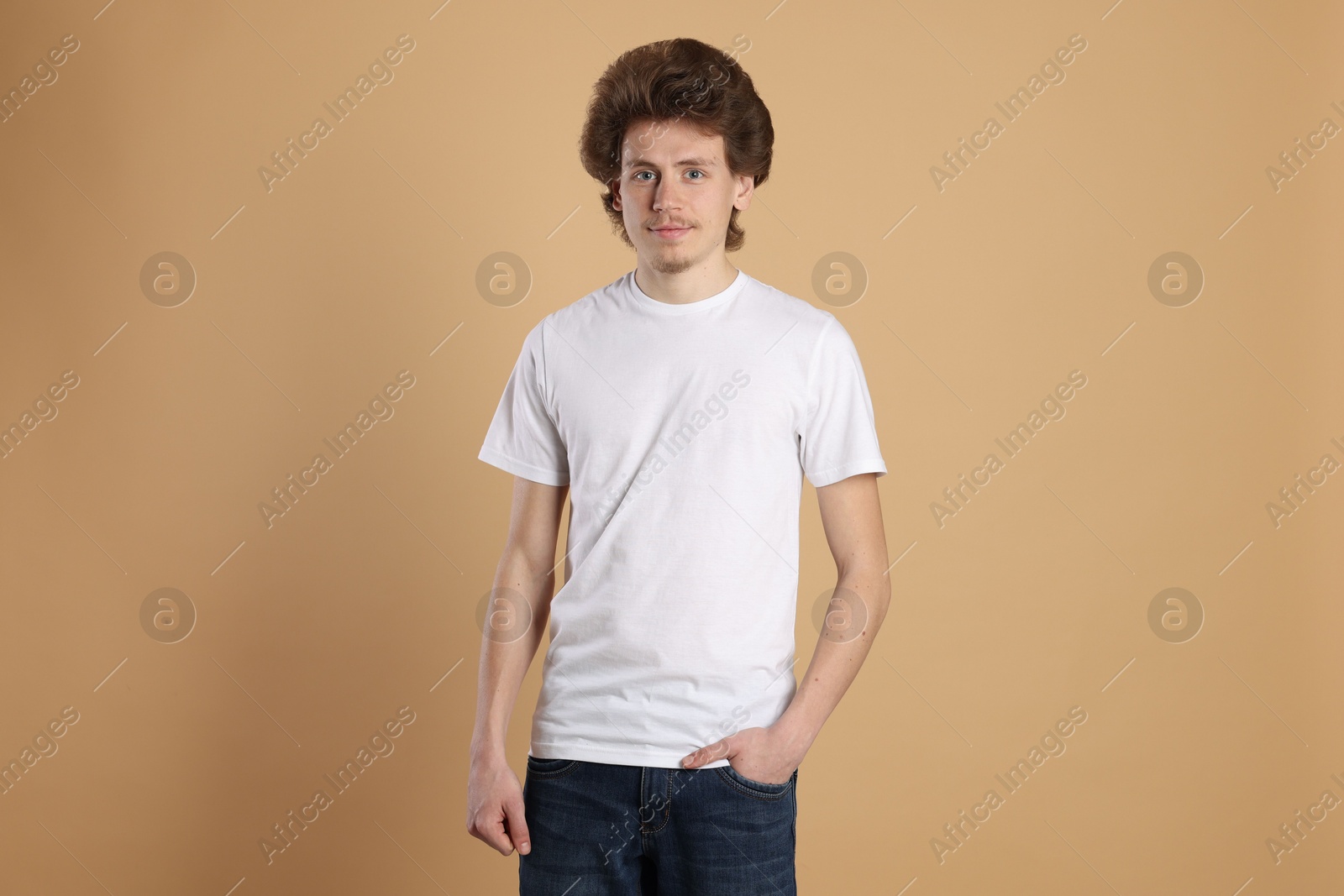 Photo of Young man wearing blank white t-shirt on light brown background. Mockup for design