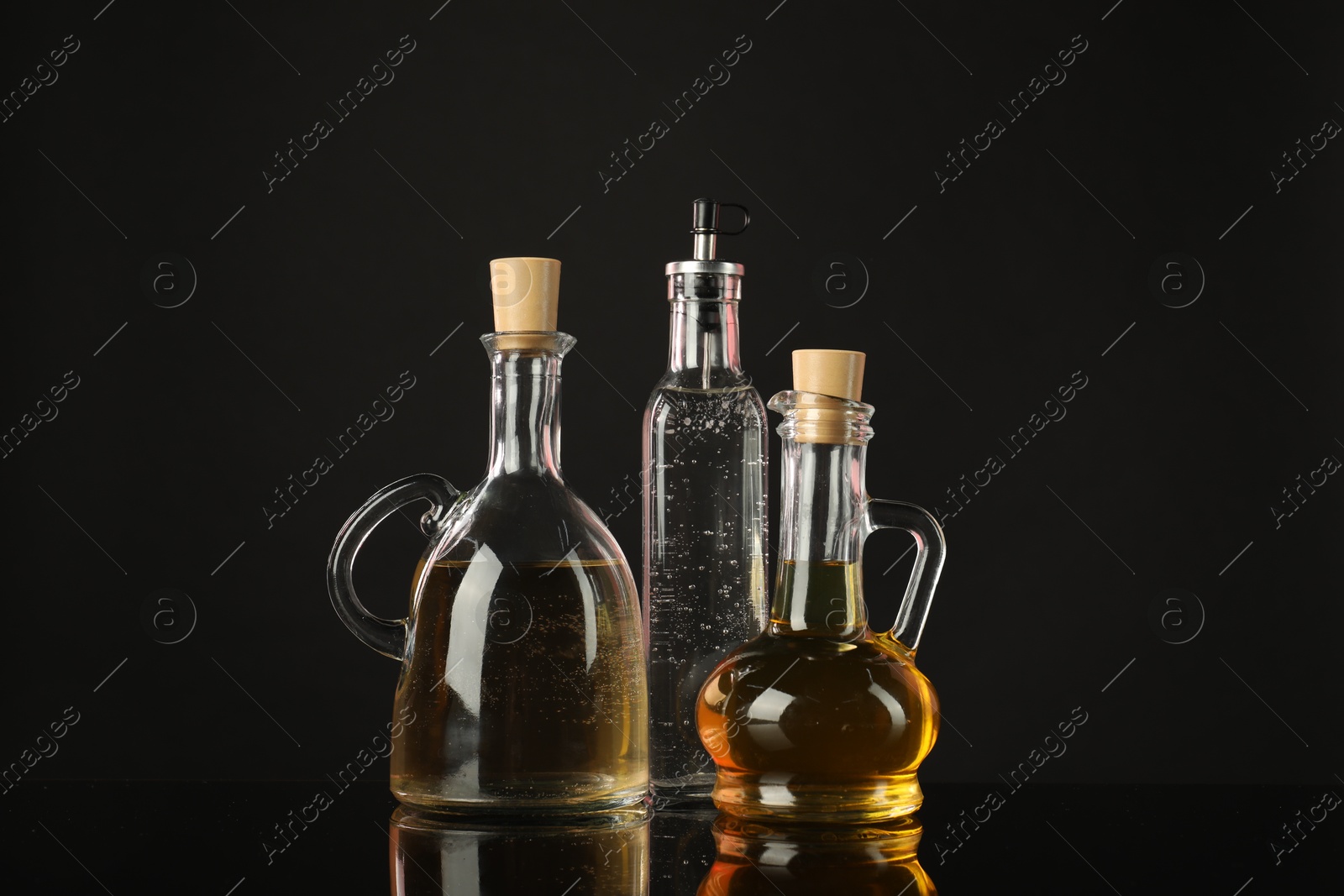 Photo of Salad dressings on mirror surface against black background