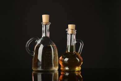 Salad dressings on mirror surface against black background