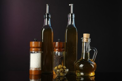 Photo of Salad dressings, spices and olives on mirror surface against dark background