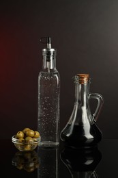 Photo of Salad dressings and olives on mirror surface against dark background