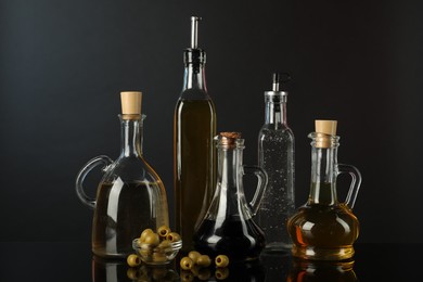 Photo of Salad dressings and olives on mirror surface against black background