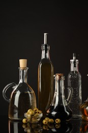 Photo of Salad dressings and olives on mirror surface against black background