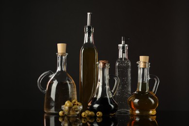 Photo of Salad dressings and olives on mirror surface against black background