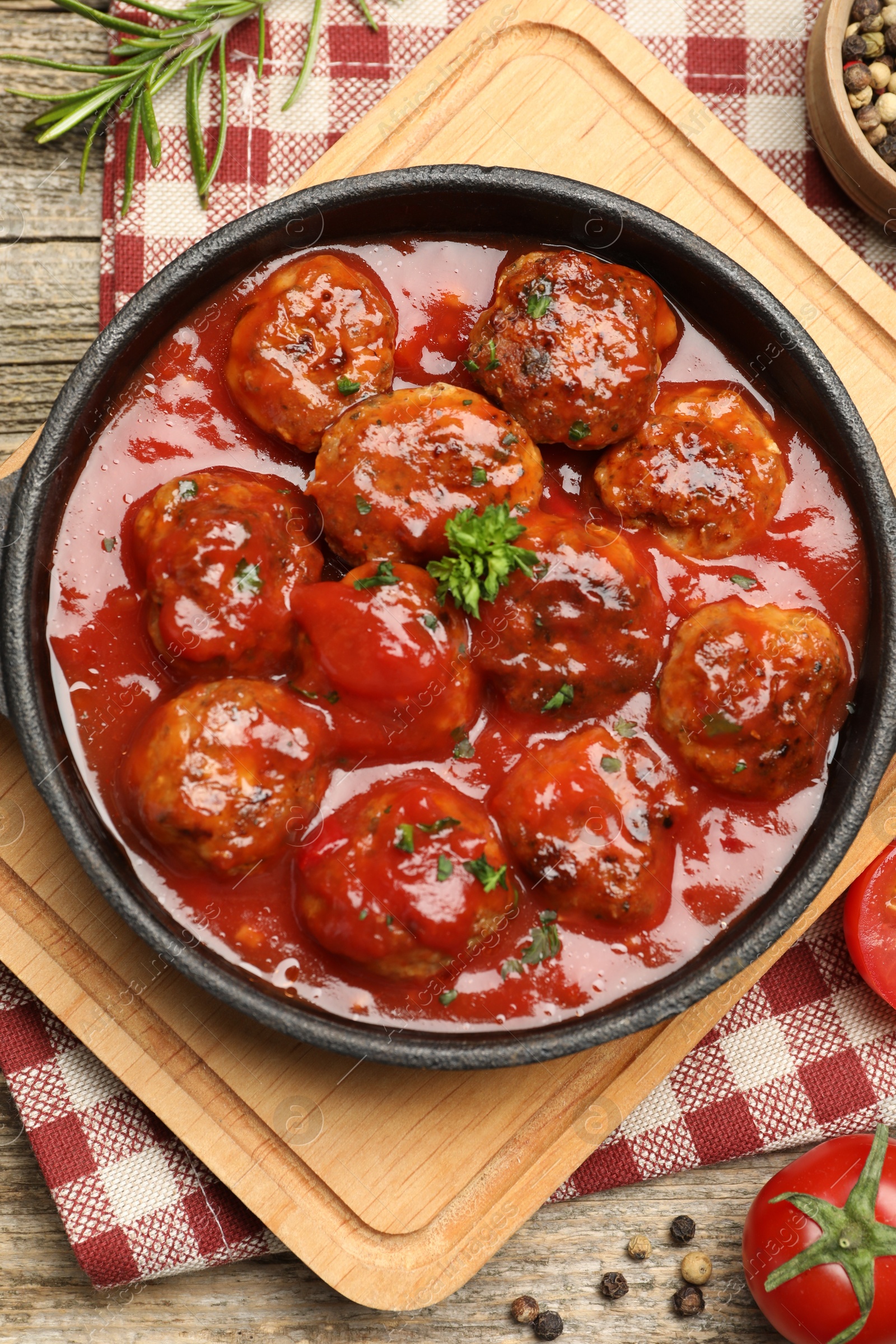 Photo of Delicious meatballs with tomato sauce in baking dish on wooden table, flat lay