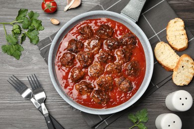 Photo of Delicious meatballs with tomato sauce served on wooden table, flat lay