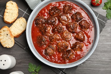 Photo of Delicious meatballs with tomato sauce served on wooden table, flat lay