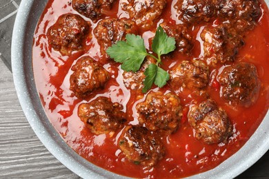 Photo of Delicious meatballs with tomato sauce in frying pan on wooden table, top view