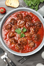 Photo of Delicious meatballs with tomato sauce served on wooden table, flat lay