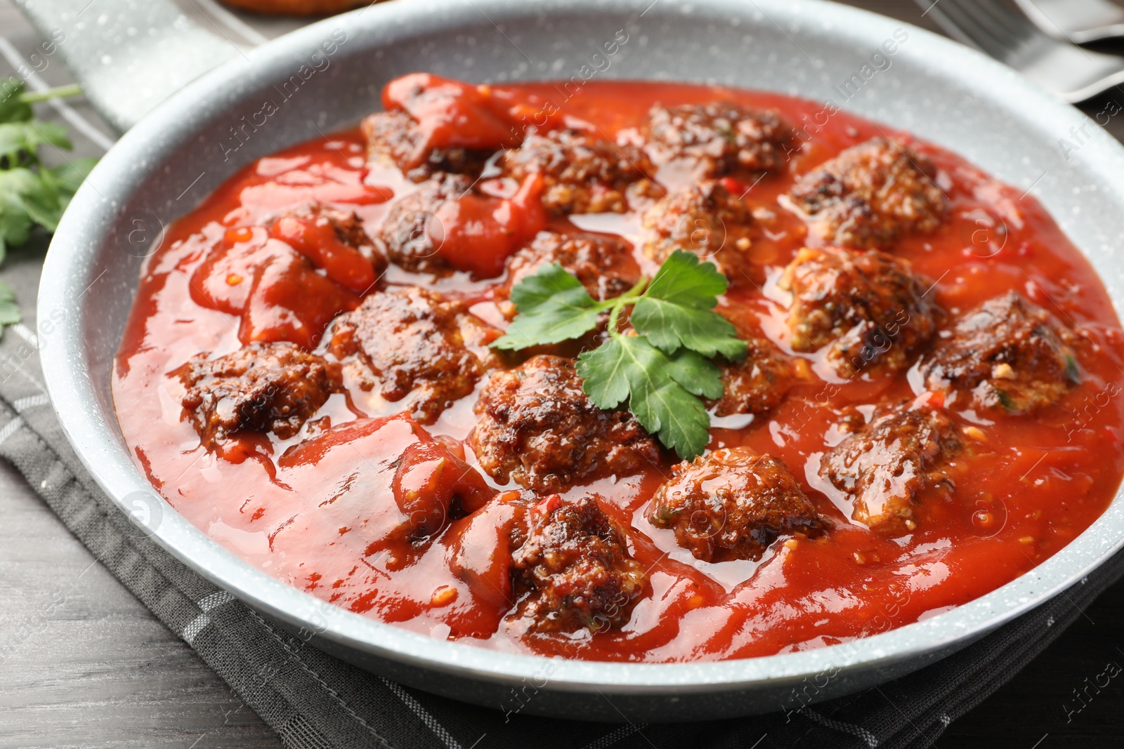 Photo of Delicious meatballs with tomato sauce in frying pan on table, closeup